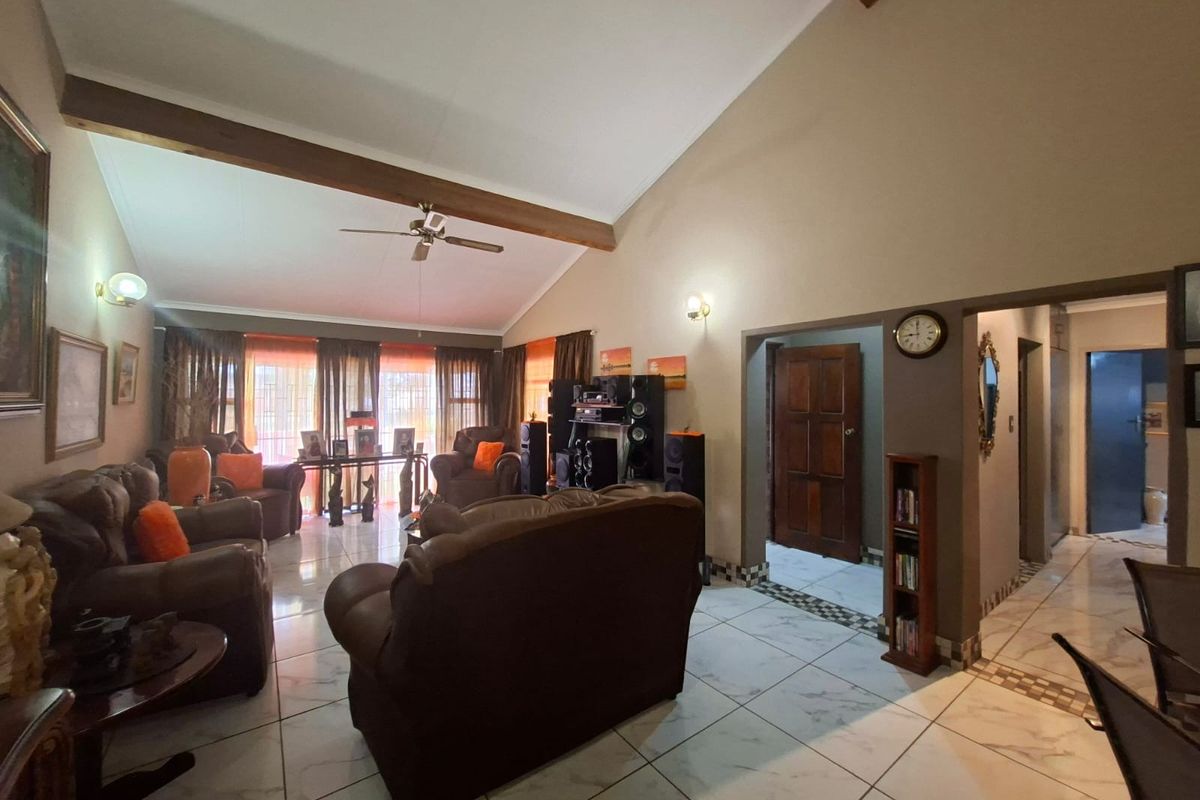 Spacious living room featuring a high vaulted ceiling with exposed timber beams, tiled flooring, and direct access to adjacent rooms.