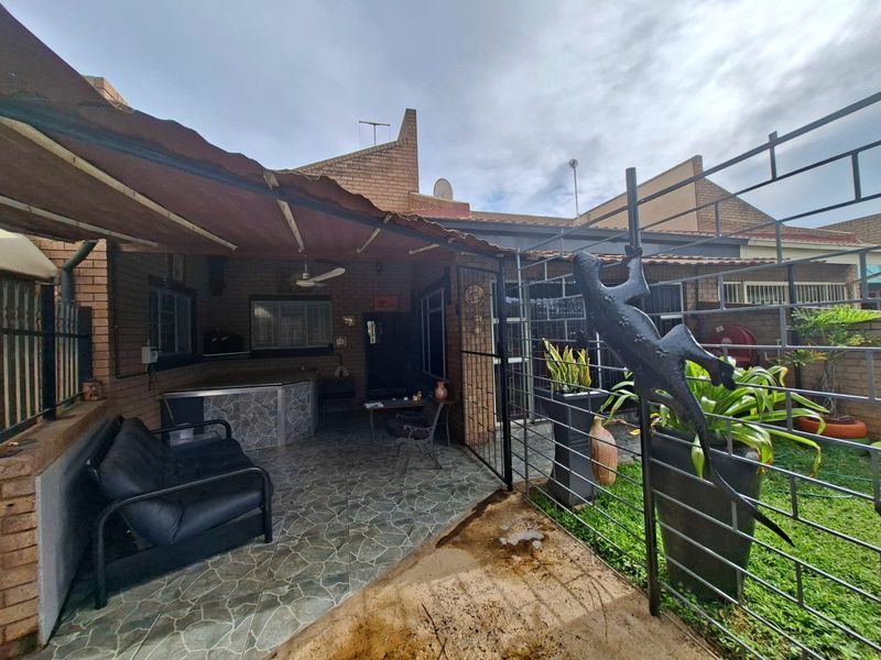 A covered outdoor patio area featuring tiled flooring, a built-in bar, and a ceiling fan, providing a functional space for outdoor entertaining.