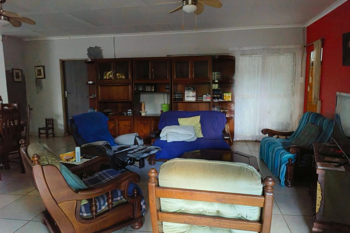 Spacious living area featuring tiled flooring, ceiling fans, and extensive built-in wooden cabinetry, offering a functional layout with potential for modernization.