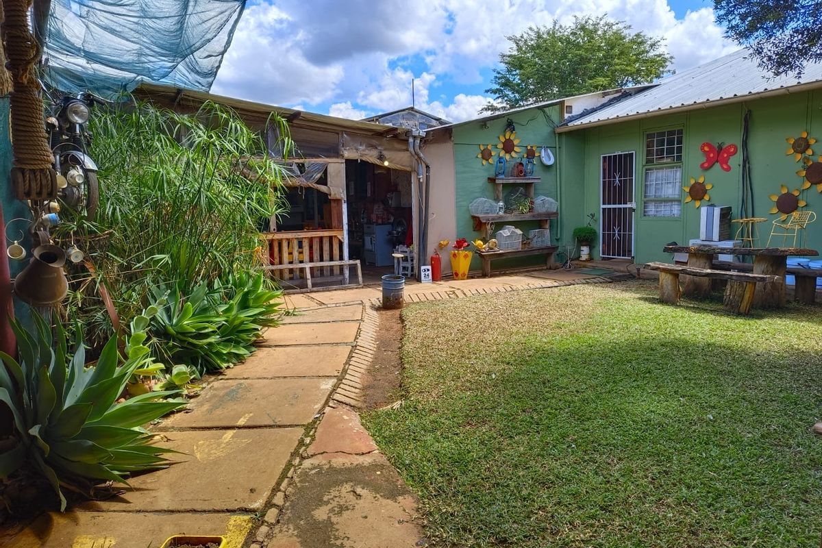 Rear garden area featuring a paved walkway, lawn, and access to the main dwelling with a covered outdoor space.