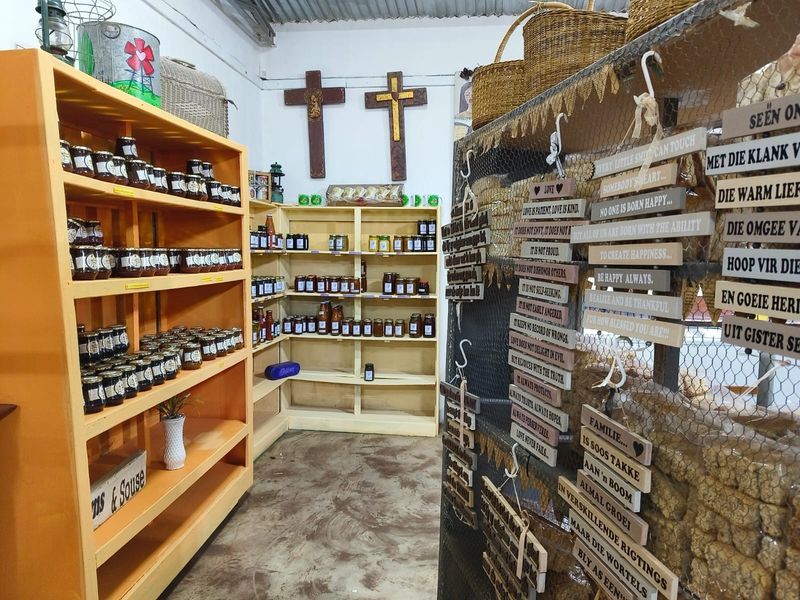 A utility or storage space featuring built-in wooden shelving units and an exposed corrugated metal ceiling, currently utilized for retail display.