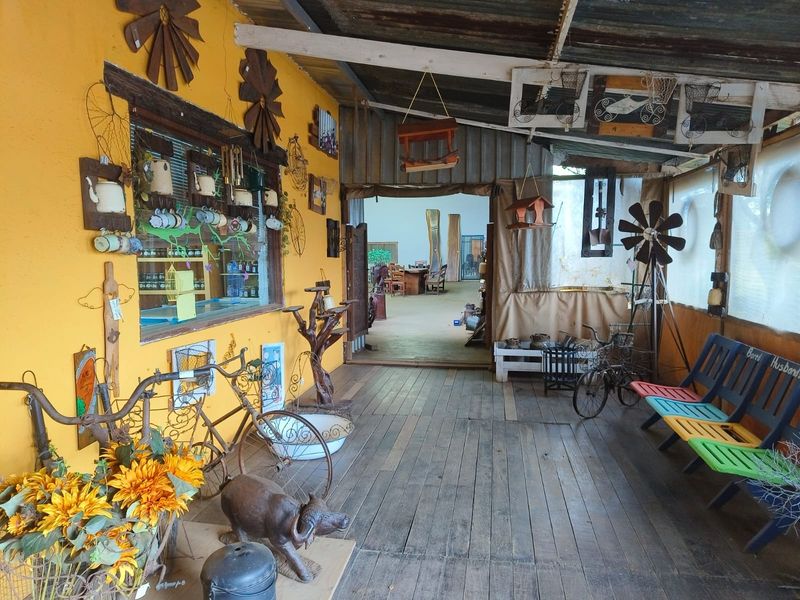 A rustic covered patio area featuring timber flooring and corrugated roofing, providing a sheltered transition space between outdoor and indoor areas.