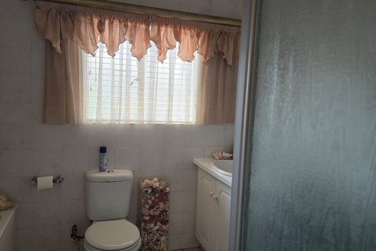 A functional bathroom featuring a built-in vanity, bathtub, and shower enclosure with tiled walls and classic fixtures.