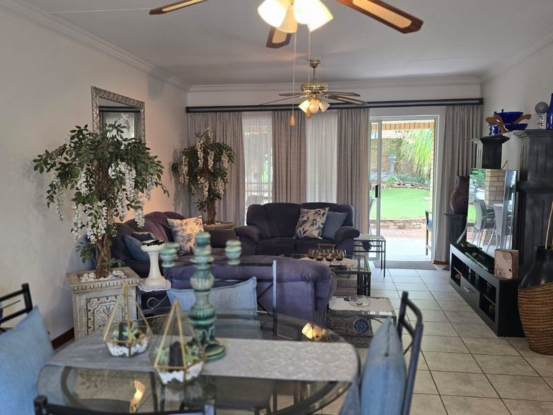 Open plan living and dining area featuring tiled flooring, ceiling fans, and sliding glass doors providing direct access to the rear garden.