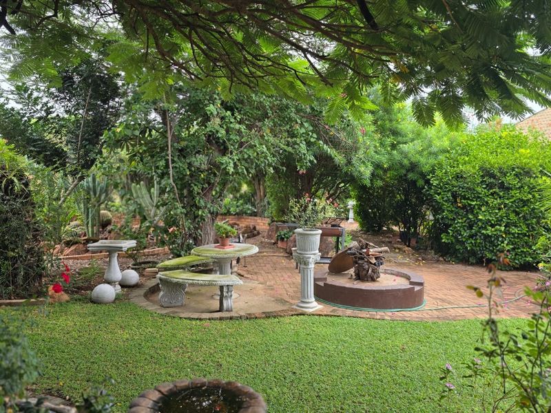 A lush, well-established garden featuring mature trees, manicured lawn, and brick-paved patio area, providing a serene and private outdoor space.