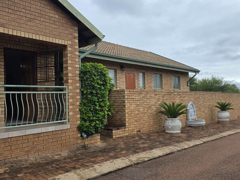 A well-maintained face brick house exterior featuring a covered entrance, paved driveway, and secure boundary walling in a quiet residential setting.
