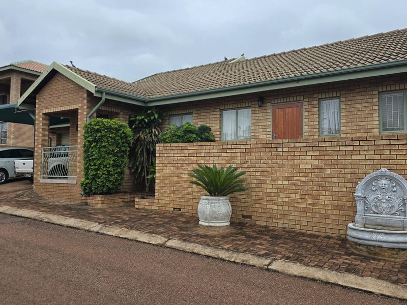 Front exterior view of a face brick house featuring a tiled roof, paved driveway, and established garden elements.