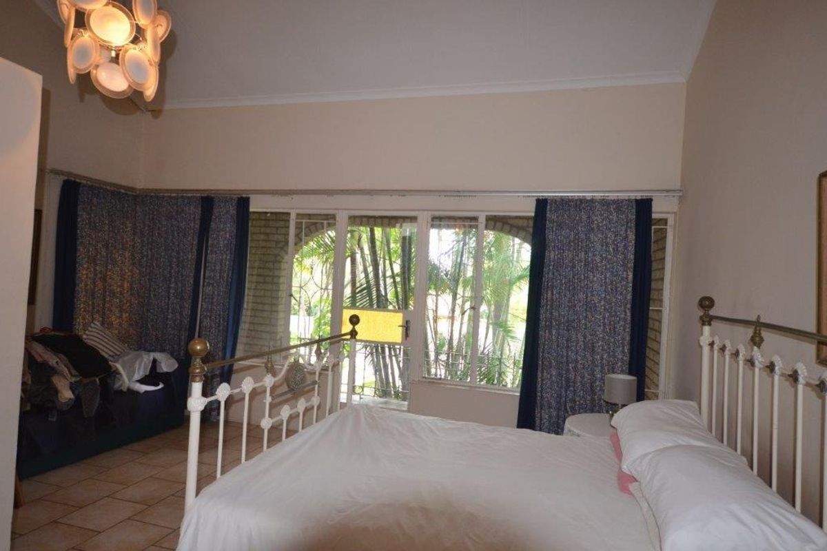 A bedroom featuring tiled flooring and large sliding glass doors that provide access to the garden area.