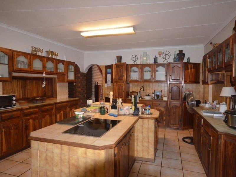 Spacious kitchen featuring extensive wooden cabinetry, tiled countertops with an integrated hob, and tiled flooring throughout.
