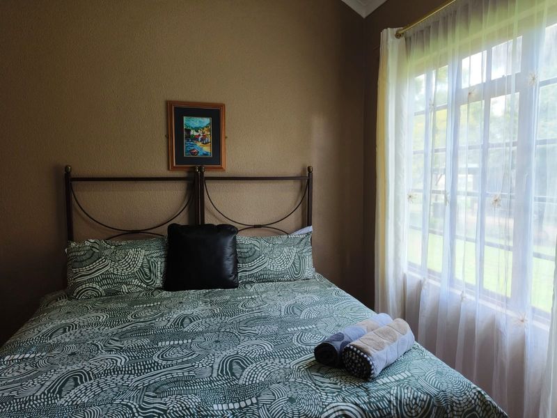 A cozy bedroom featuring a window with natural light, neutral wall tones, and a classic layout suitable for a comfortable sleeping space.