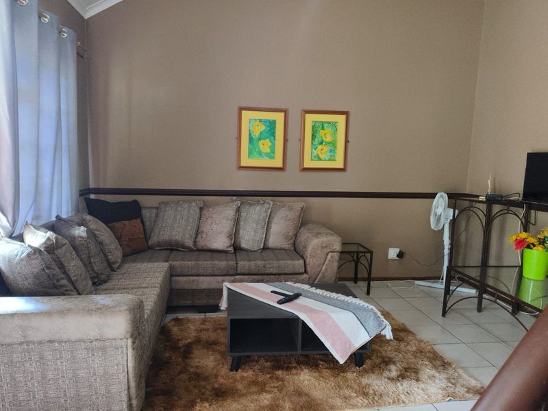 A comfortable living room featuring tiled flooring, a chair rail, and a vaulted ceiling, providing a functional and inviting space.