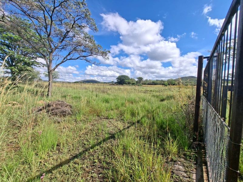 A view of the vacant residential land featuring natural grass coverage and existing metal perimeter fencing.