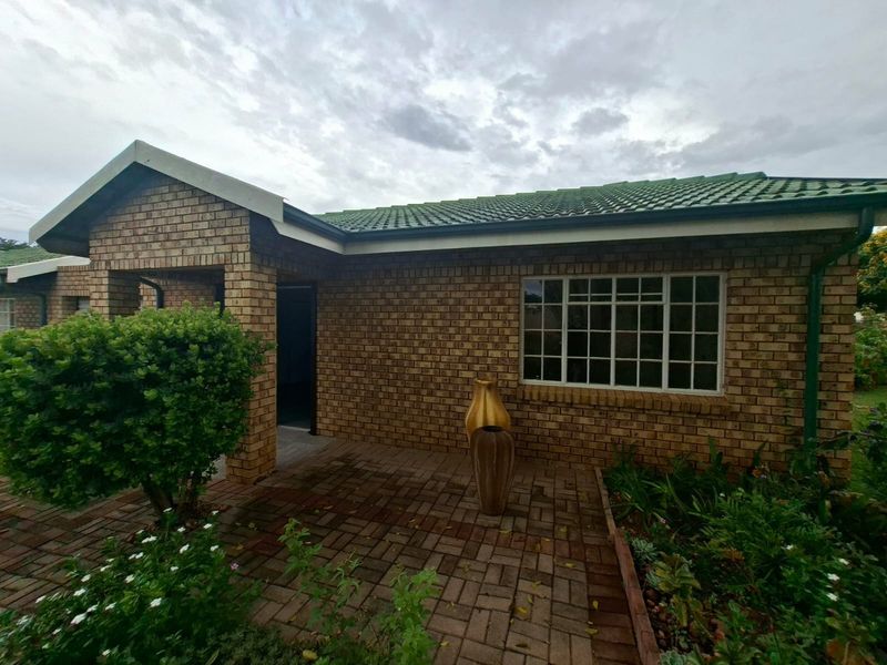 A well-maintained retirement village unit featuring a classic face brick exterior, tiled roof, and a private paved entrance area.