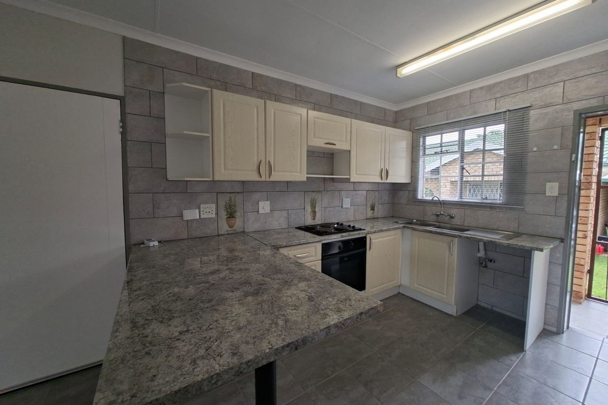 A functional kitchen featuring built-in cabinetry, laminate countertops, a built-in oven with gas hob, and tiled backsplash, offering a clean and practical workspace.