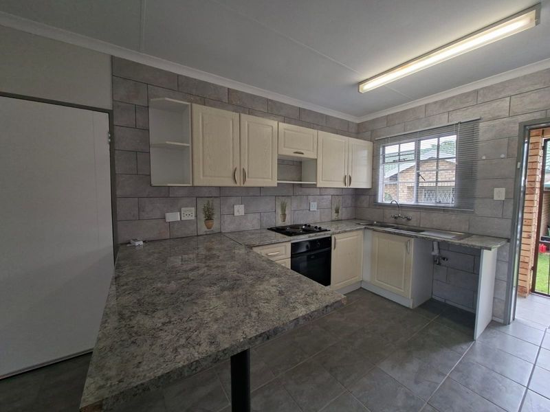 A functional kitchen featuring built-in cabinetry, laminate countertops, a built-in oven with gas hob, and tiled backsplash, offering a clean and practical workspace.