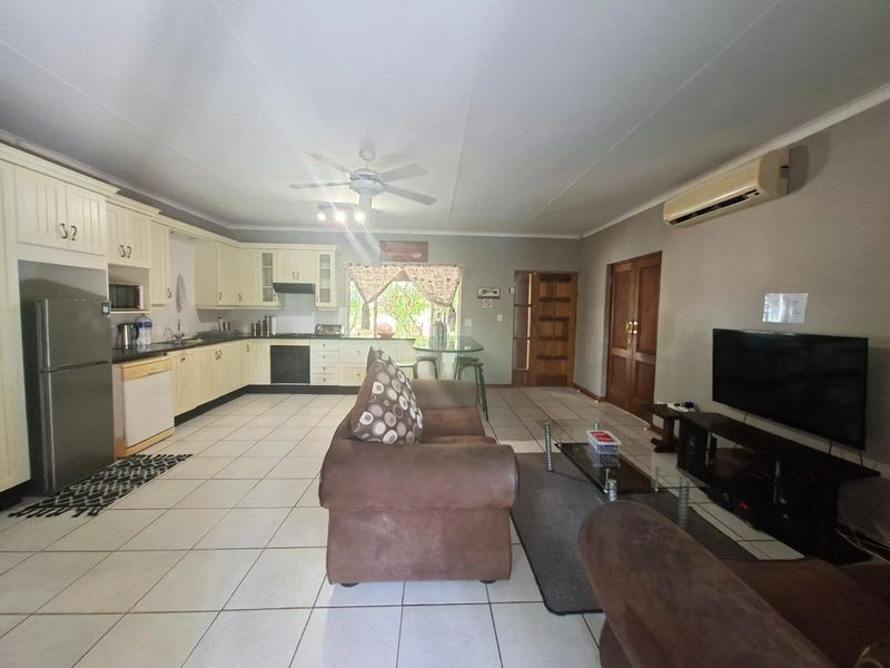 Spacious open-plan living area featuring a functional kitchen with built-in cabinetry, tiled floors, and a split-system air conditioner for climate control.