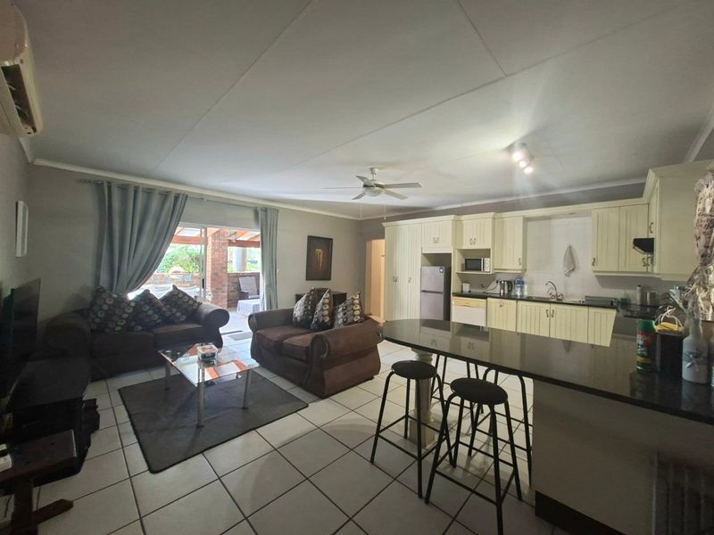 Open-plan living area featuring a kitchen with granite countertops and island, tiled flooring, and direct access to an outdoor patio through sliding glass doors.
