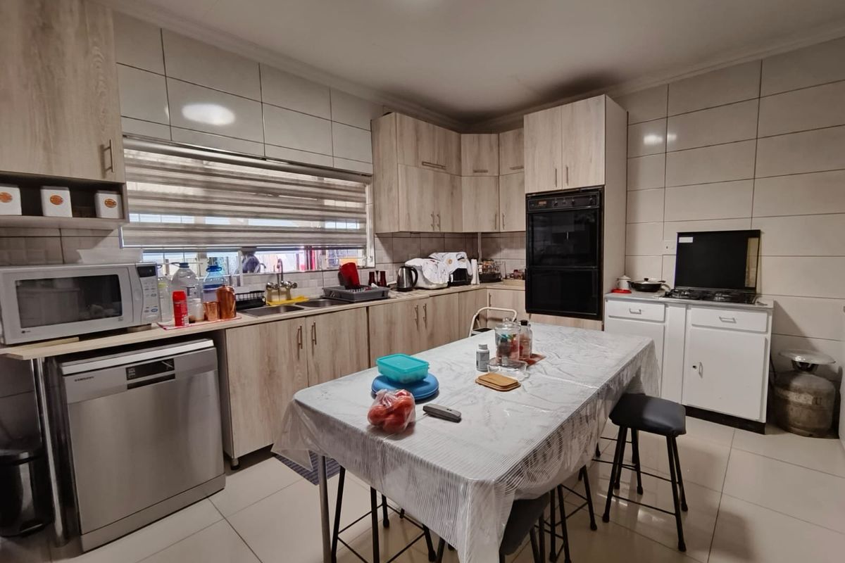 A functional kitchen featuring light wood-look cabinetry, a double wall oven, tiled splashbacks, and tiled flooring with ample storage space.