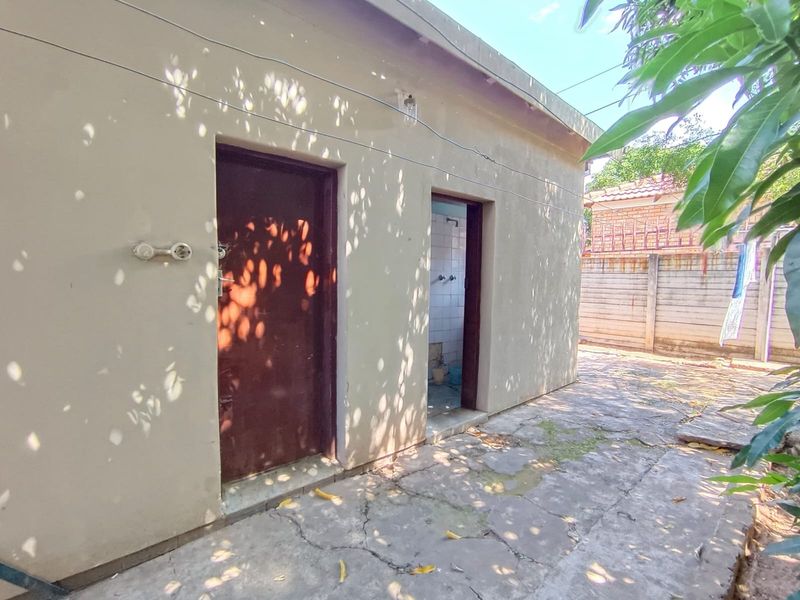 Rear exterior view of the property showing a paved courtyard area with access doors to utility or service rooms.