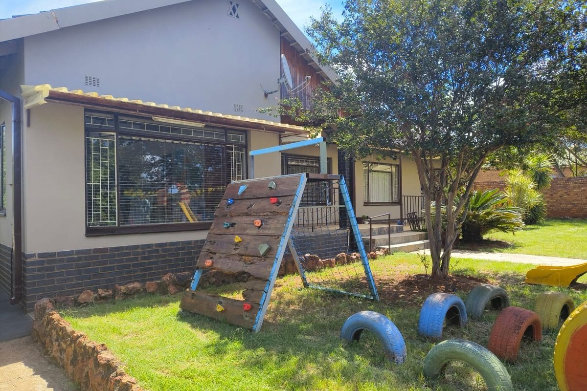 Rear view of the house featuring a garden area with stone edging, security bars on windows, and a satellite dish mounted on the wall.