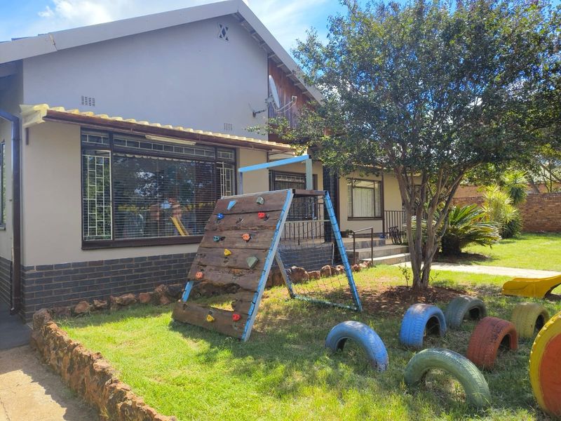 Rear view of the house featuring a garden area with stone edging, security bars on windows, and a satellite dish mounted on the wall.