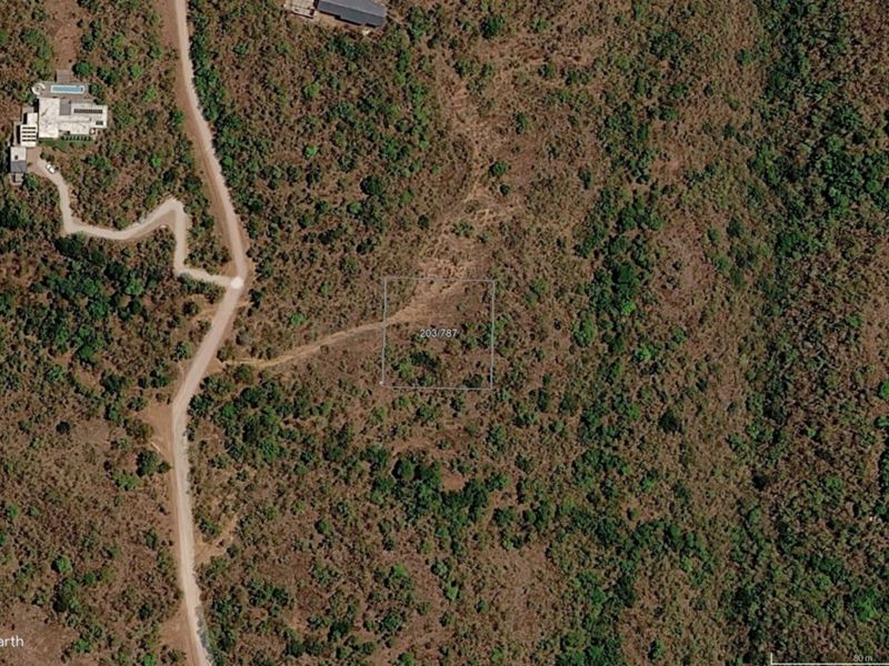 Aerial view of a vacant residential plot featuring natural vegetation and surrounding landscape in a quiet estate setting.