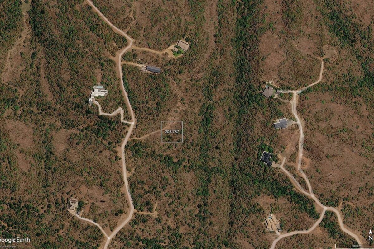 Aerial view of a vacant residential plot situated within a natural landscape, featuring surrounding access roads and nearby established properties.