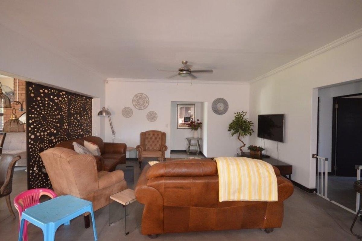 A spacious living room featuring a ceiling fan and a decorative laser-cut partition screen, offering a versatile layout for relaxation and entertainment.