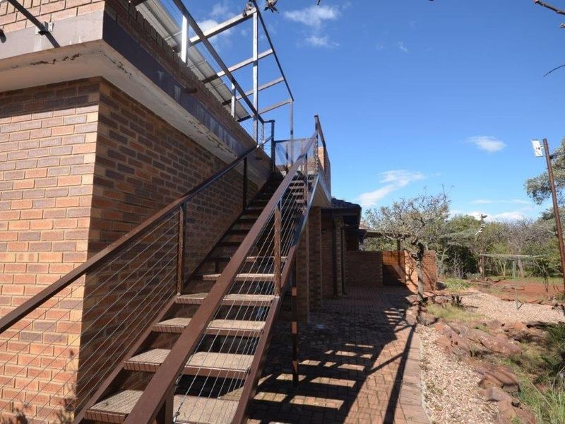 Rear exterior view featuring a brick facade, paved patio area, and an external metal staircase leading to an upper level.