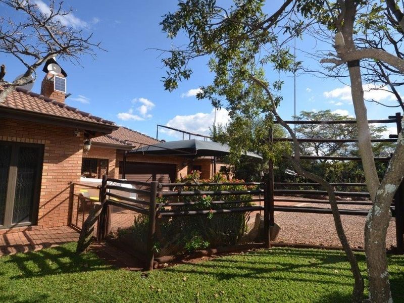 Rear view of the brick house featuring a paved patio area, timber fencing, and a well-maintained garden space.