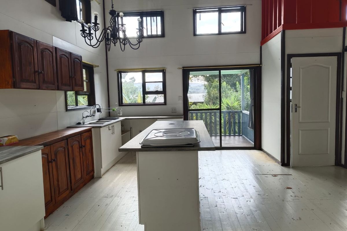 Spacious kitchen featuring a central island with built-in hob, wooden cabinetry, and direct access to an outdoor balcony through sliding glass doors.