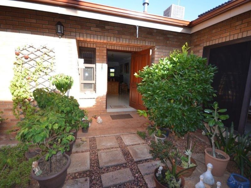 A private rear courtyard featuring a brick facade, paved pathway, and direct access to the home through a timber entrance door.