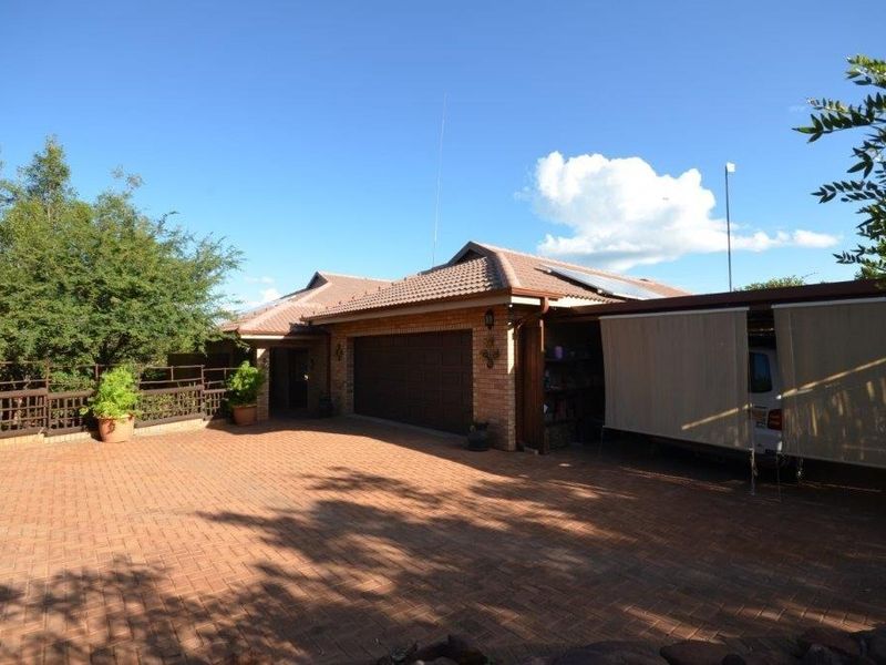 Front exterior view of the house featuring a brick driveway, double garage, and an attached carport with a tiled roof.
