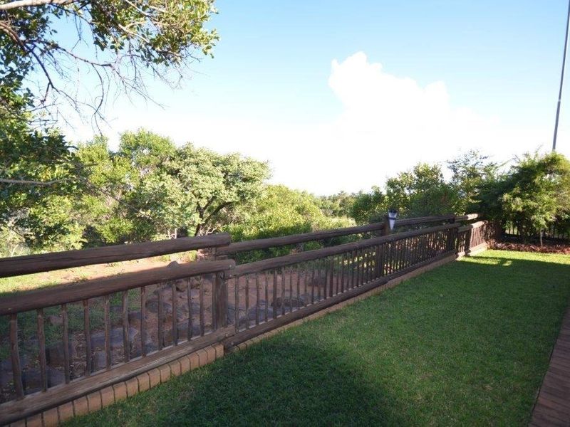 A well-maintained garden area featuring a timber balustrade, brick paving, and established greenery with a natural outlook.