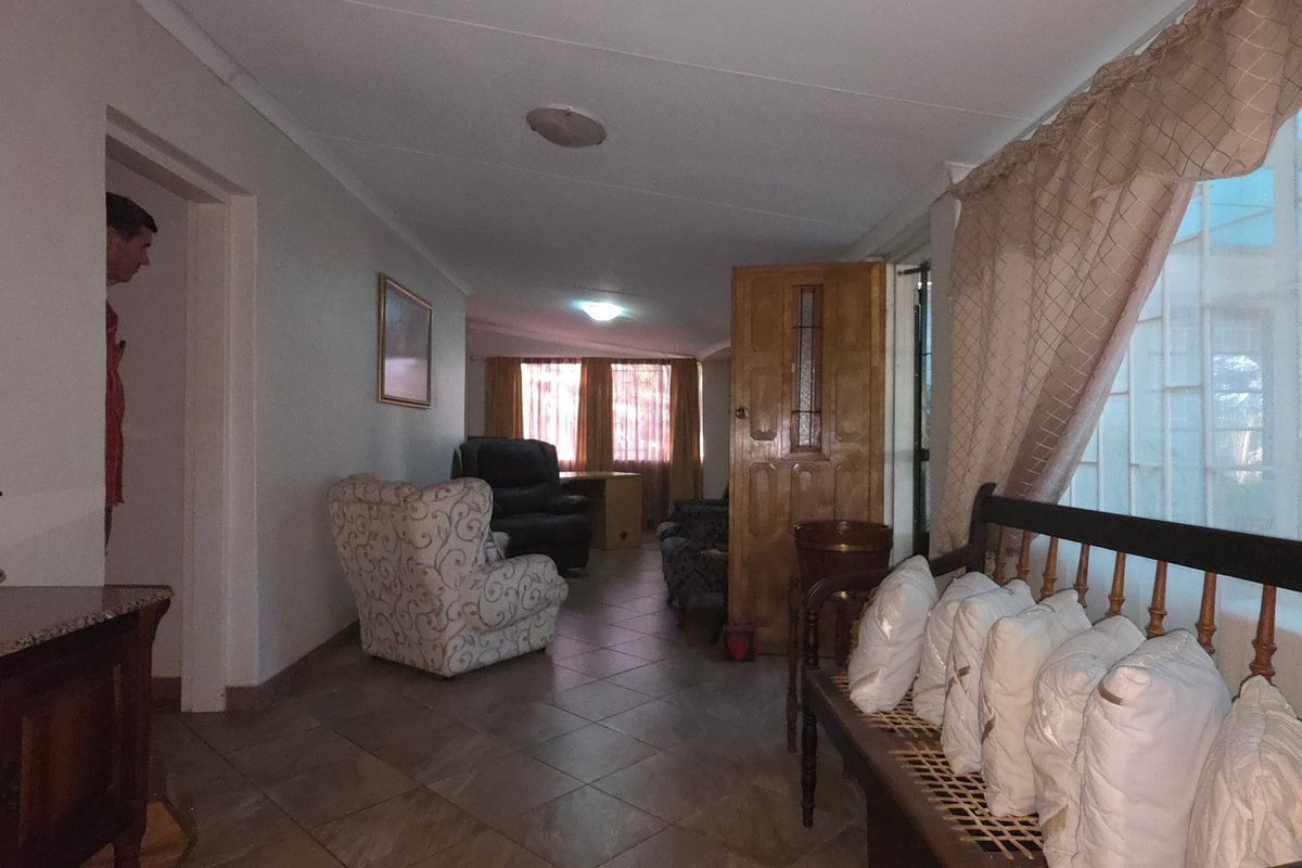 A living area featuring tiled flooring and a wooden door, providing a functional space with natural light access.