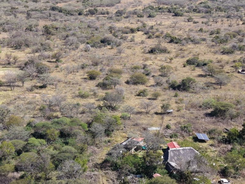 Aerial view of a small holding property featuring natural bushveld landscape, a main dwelling with a thatched roof, and installed solar panels.