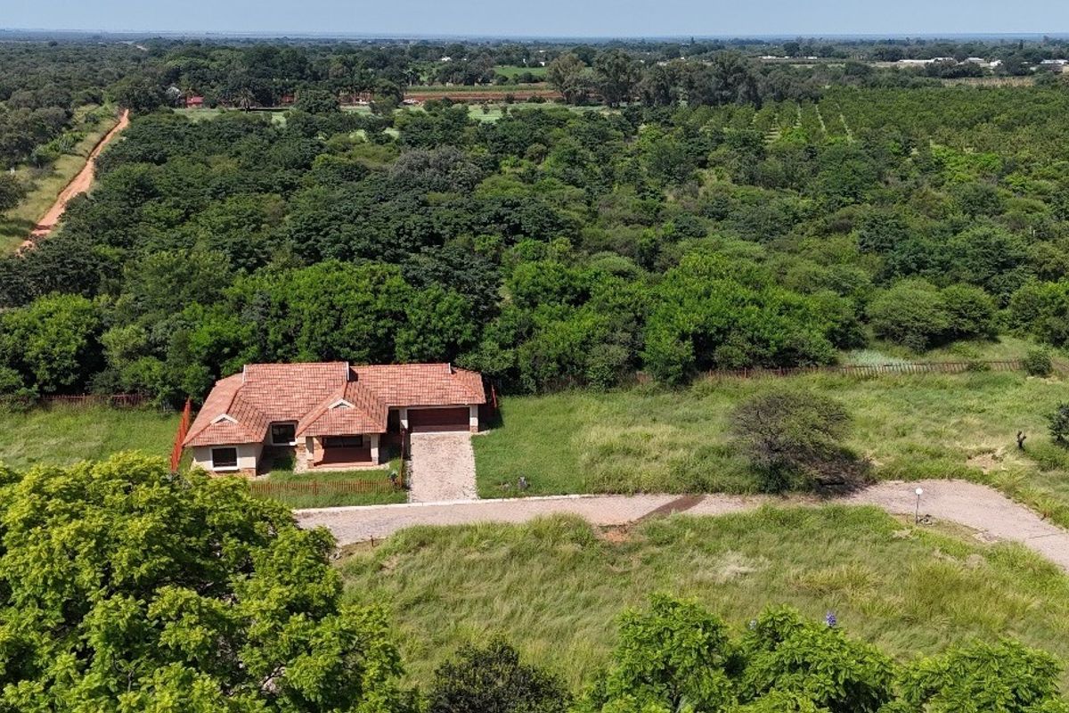 Aerial view of a residential property featuring a tiled roof home, paved driveway, and surrounding natural landscape.
