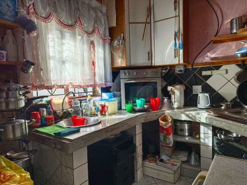 A dated kitchen featuring concrete countertops, built-in oven, and tiled backsplash, requiring significant renovation to modernize the space and improve functionality.