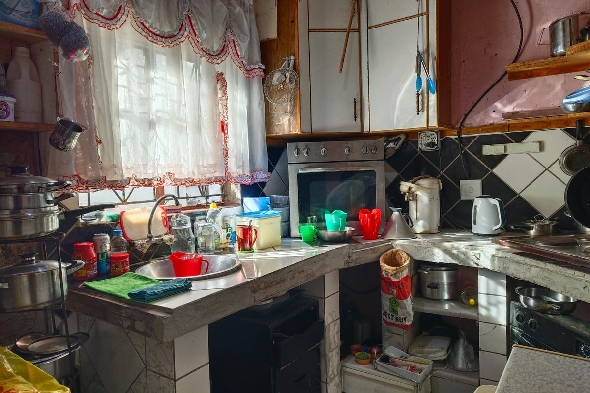 A dated kitchen featuring concrete countertops, built-in oven, and tiled backsplash, requiring significant renovation to modernize the space and improve functionality.