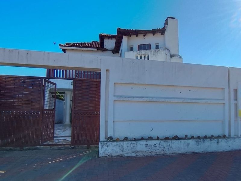Front exterior view of a multi-story house featuring a boundary wall, metal entrance gate, and tiled roof architecture.