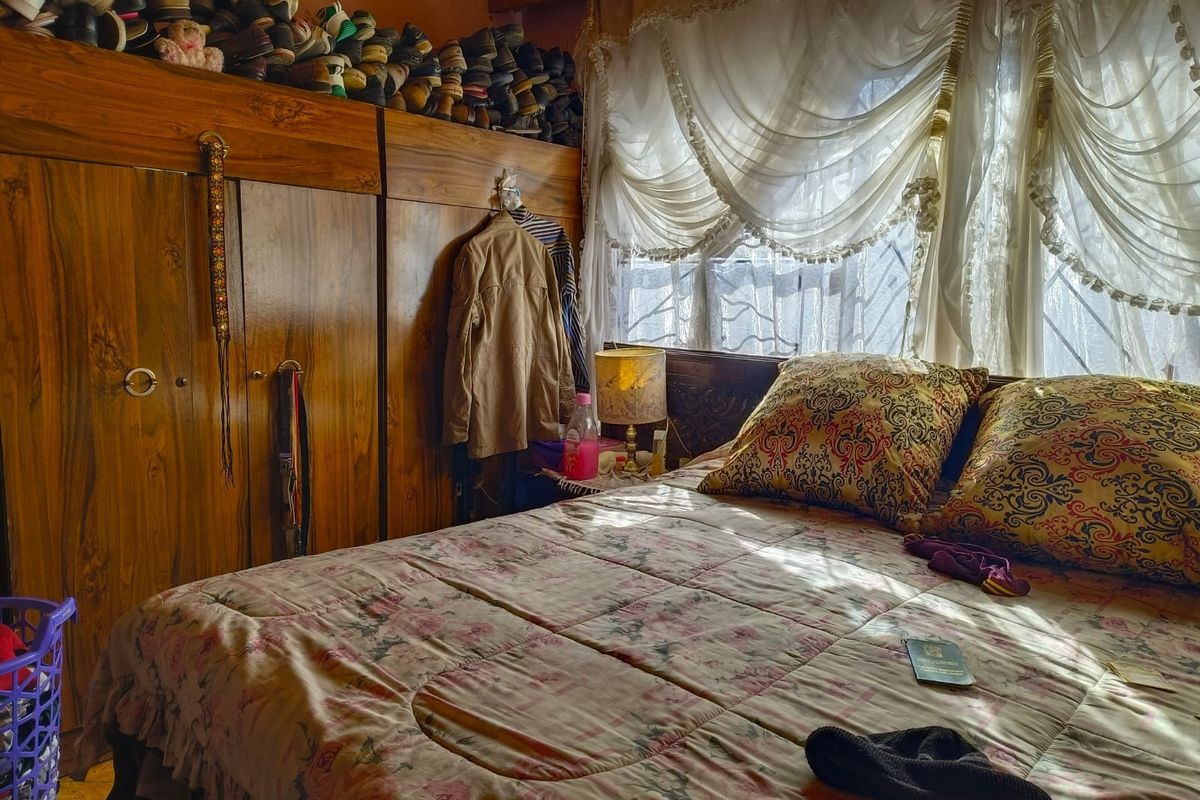 A bedroom featuring a large built-in wooden wardrobe and a window fitted with security bars, providing natural light to the space.