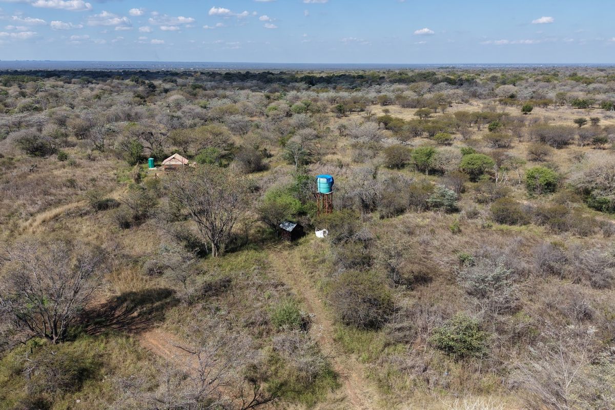 Aerial view of the farm property showing natural bushveld landscape, a water storage tank, and small outbuildings.