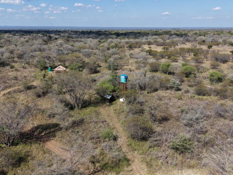 Aerial view of the farm property showing natural bushveld landscape, a water storage tank, and small outbuildings.