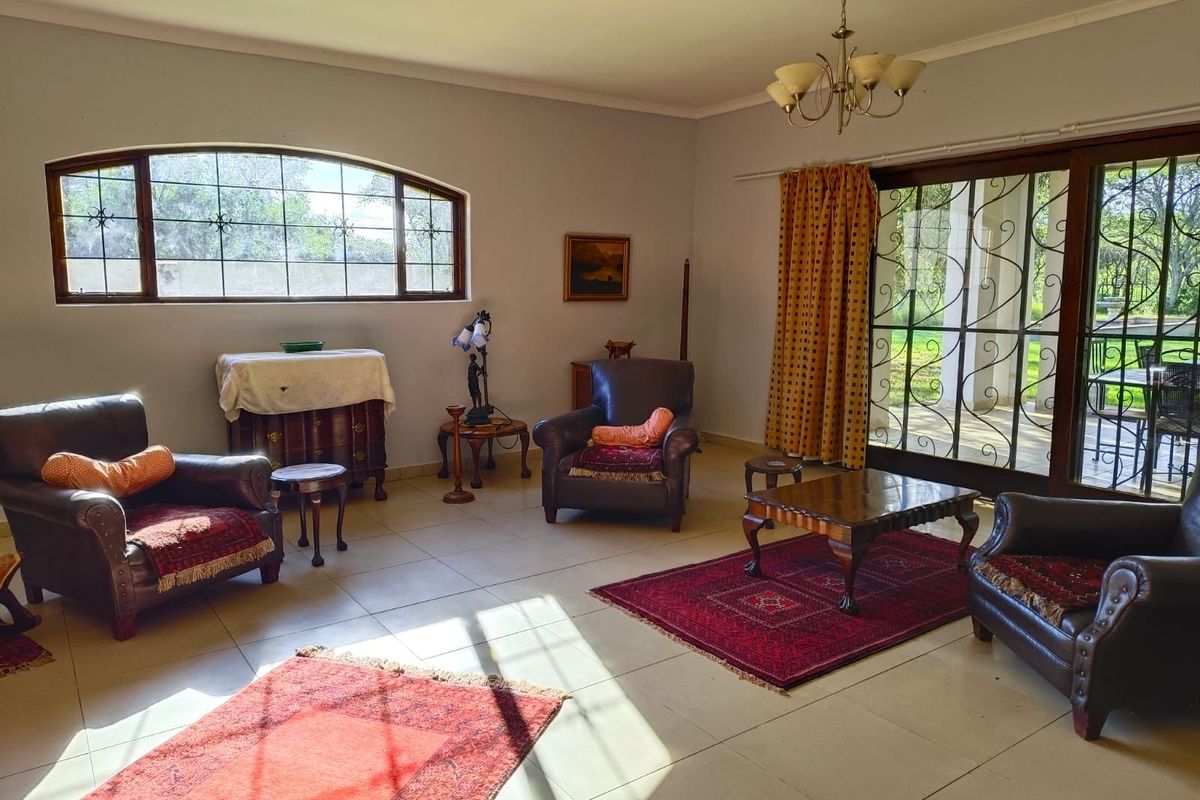 Spacious living room featuring tiled flooring, an arched window, and large sliding doors with security gates leading to the outdoor patio area.