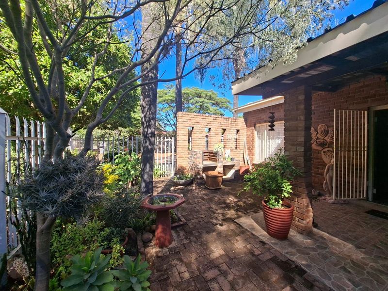 A private rear courtyard featuring brick paving, a built-in brick braai, and established garden landscaping, providing a functional outdoor entertainment space.