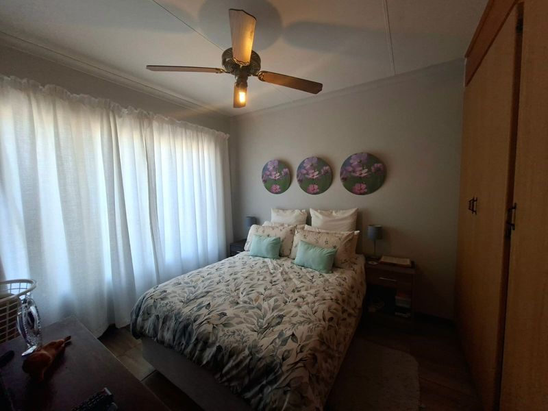 A cozy bedroom featuring a ceiling fan and a built-in wardrobe, offering a functional and comfortable living space.