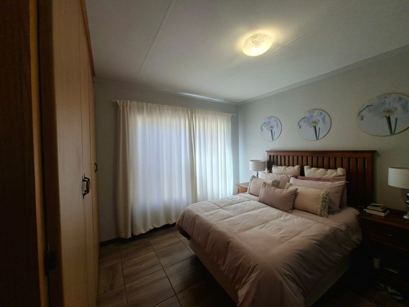 A well-maintained bedroom featuring tiled flooring, a built-in wardrobe, and neutral wall finishes, providing a comfortable and functional living space.
