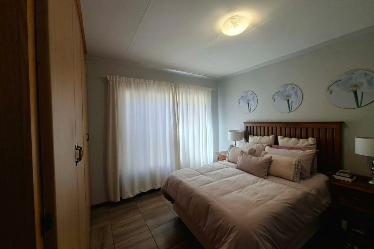 A well-maintained bedroom featuring tiled flooring, a built-in wardrobe, and neutral wall finishes, providing a comfortable and functional living space.