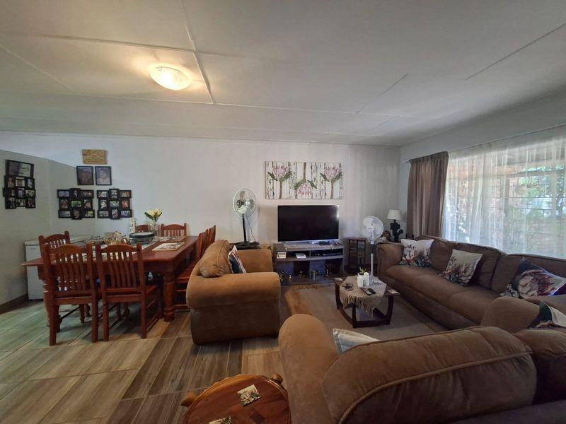 Spacious open-plan living and dining area featuring tiled flooring and a neutral layout, offering a versatile space for family living.