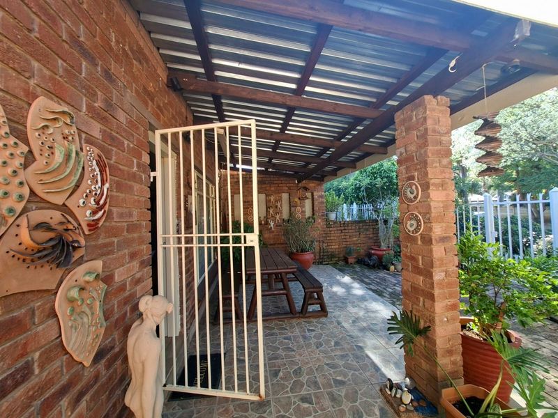 A covered outdoor patio featuring exposed brick walls, timber roof beams, and durable tiled flooring, providing a sheltered space for outdoor relaxation.